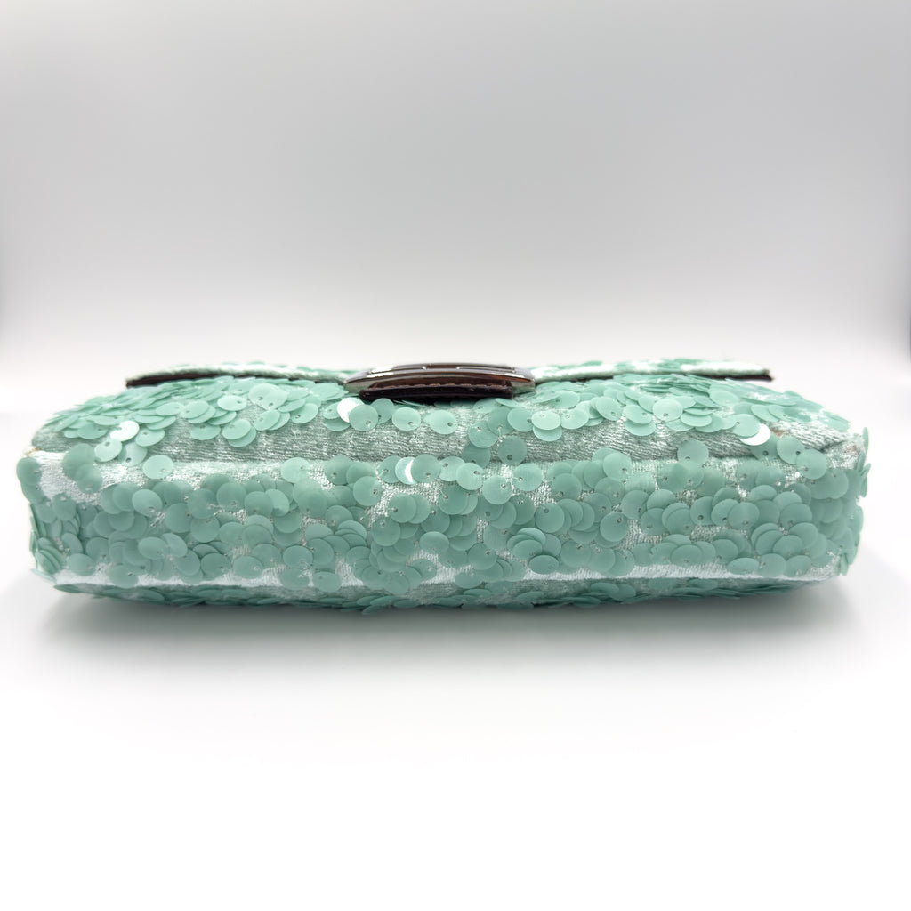 A mint green sequined clutch bag with a dark brown leather strap, shown against a neutral light gray background.