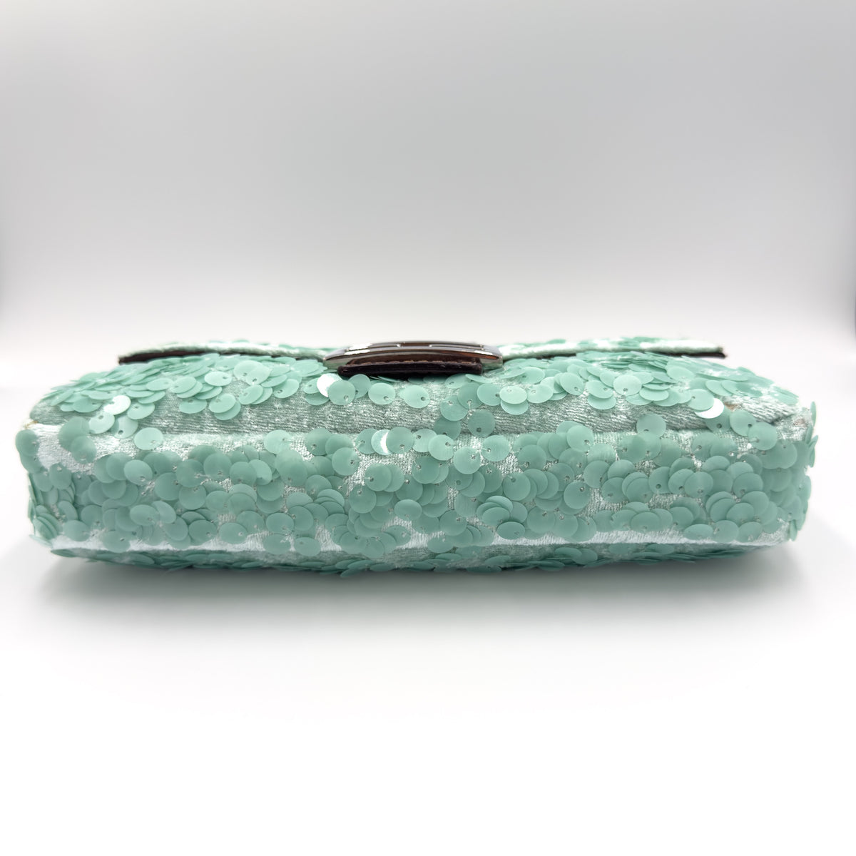 A mint green sequined clutch bag with a dark brown leather strap, shown against a neutral light gray background.